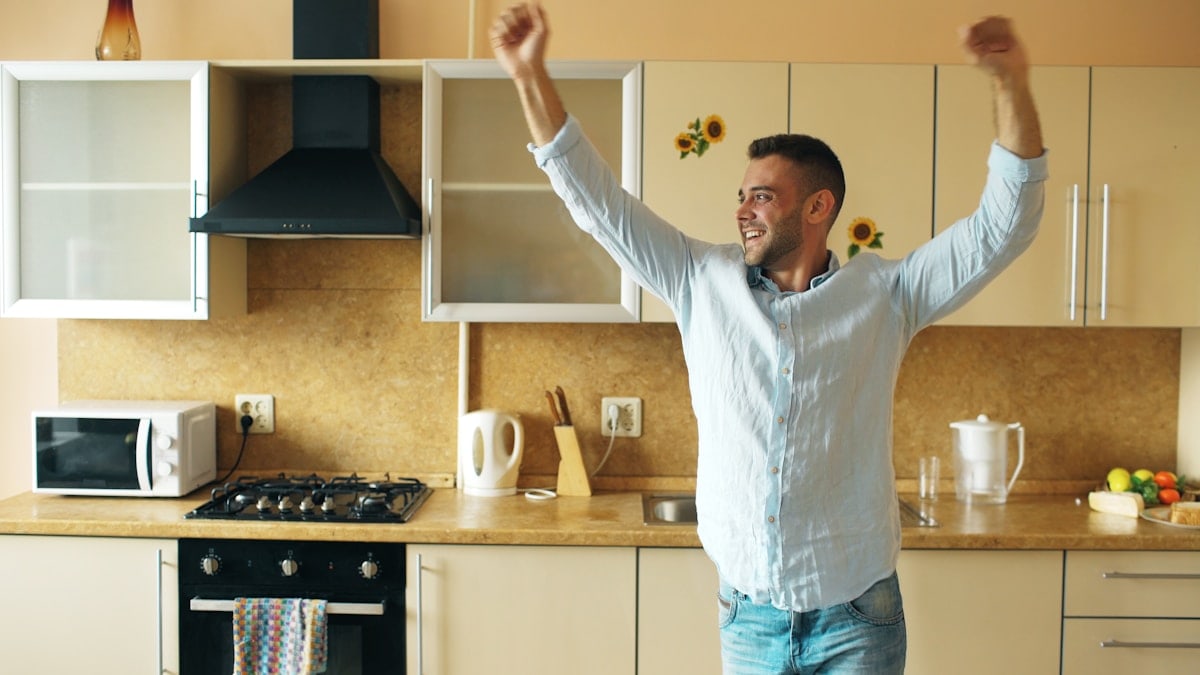 Handsome young funny man dancing in kitchen at home in the morning and have fun on vacation